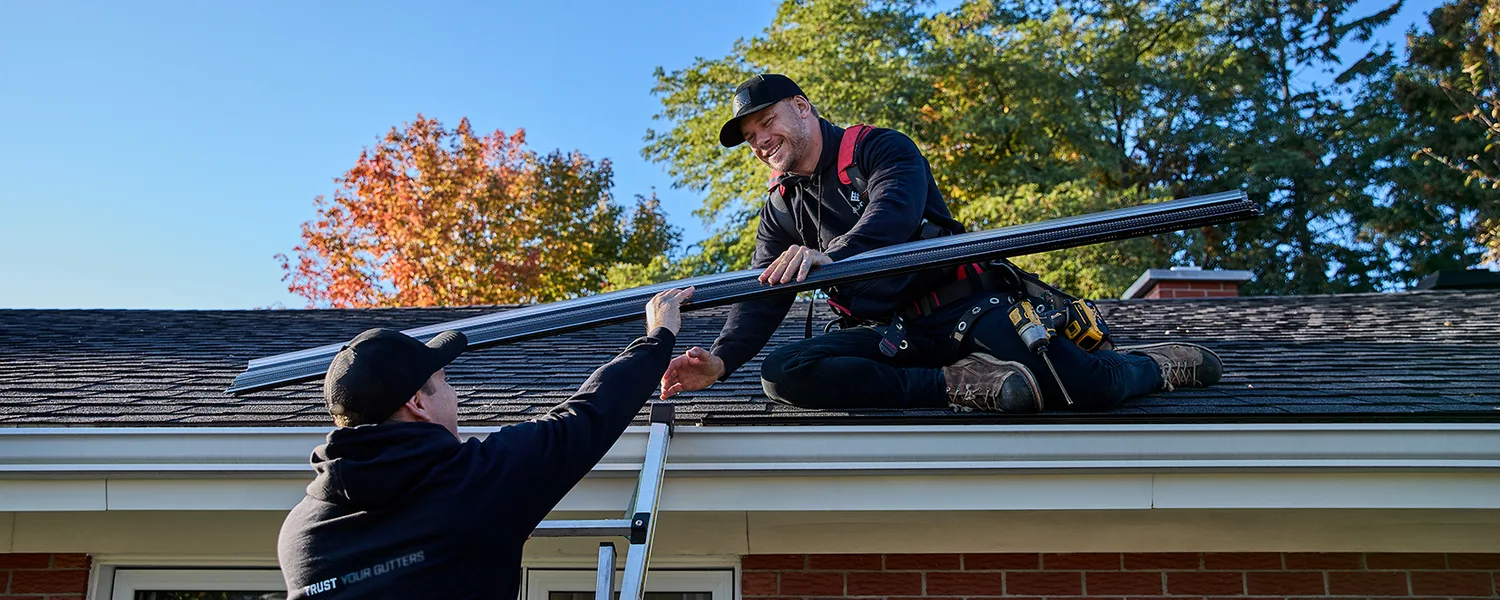 Installer carrying gutter stock toward a residential project