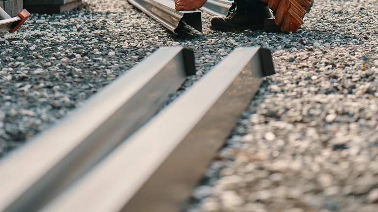 Technician clearing leaves and debris from a gutter before Michigan freeze-up