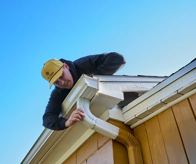 Installer setting a seamless gutter at the roofline