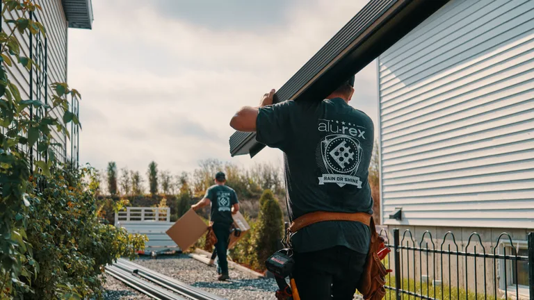 Installer carrying a custom seamless gutter along a home
