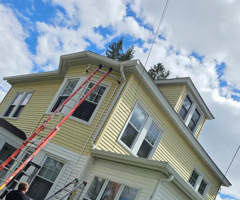 Tyler installing gutters on a two-storey home in Biddeford