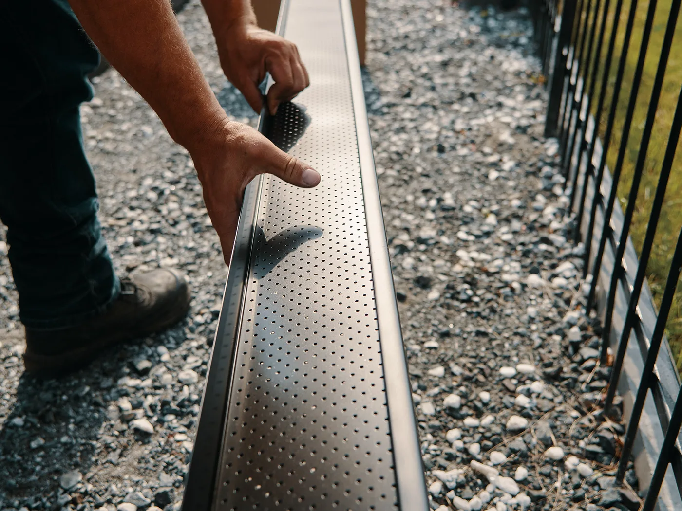 Installer carrying a new seamless gutter up a ladder
