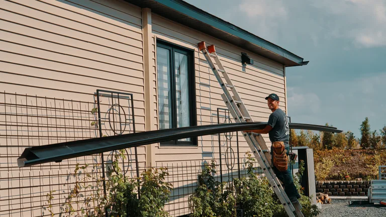 Installer carrying a seamless gutter up a ladder
