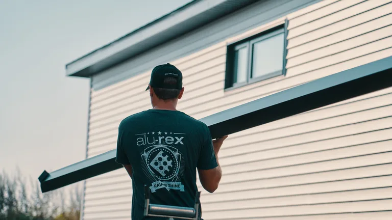 Installer carrying seamless gutter material at a Fairborn-area home