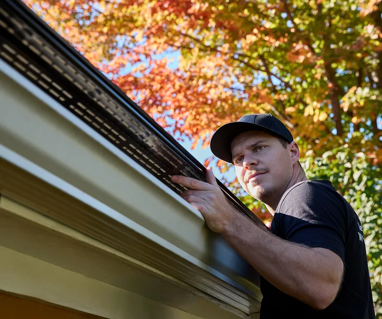Contractor inspecting the roofline before a gutter installation