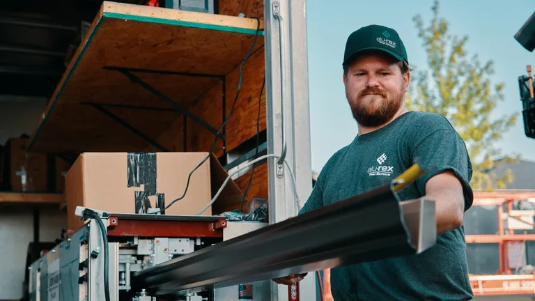 Installer carrying seamless gutter material at a Fairborn-area home